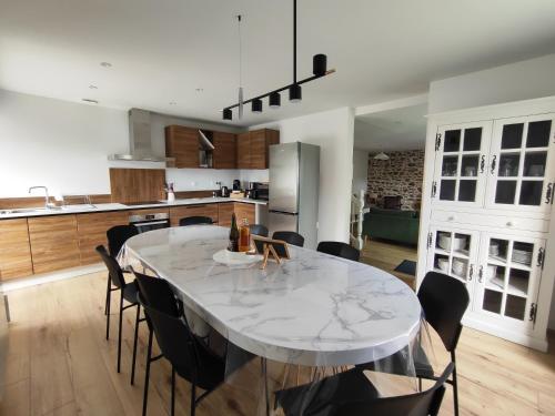 eine Küche mit einem großen weißen Tisch und Stühlen in der Unterkunft Tata Jacqueline, grand gîte proche mer, Bretagne in Plouha