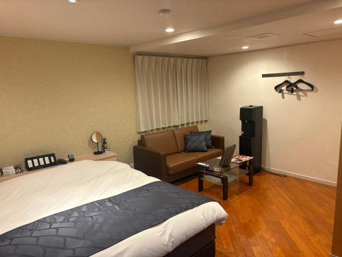 a bedroom with a bed and a couch at Hotel VALENTINE GLOW in Toride