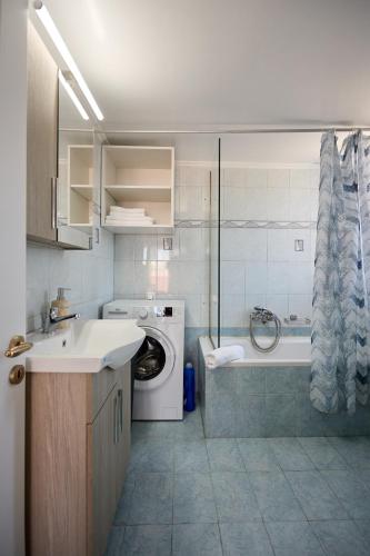 a bathroom with a washing machine and a bath tub at ChioSmart Kontari Apartments in Chios