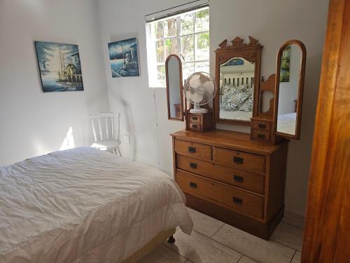 a bedroom with a bed and a dresser with a mirror at Valley Cottage in Kenton on Sea