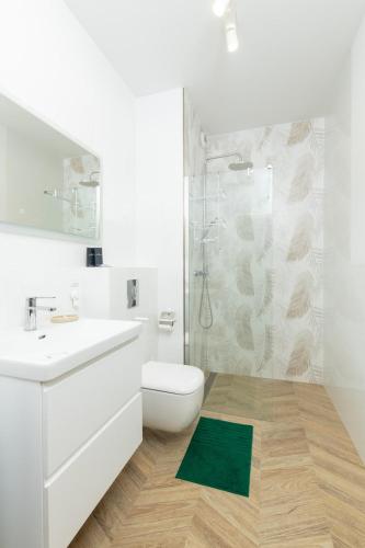 a white bathroom with a toilet and a shower at Tabago Studio 39 Skierniewice in Skierniewice