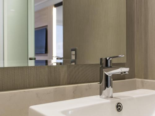 a bathroom sink with a faucet and a mirror at Pullman Vina del Mar San Martin in Viña del Mar