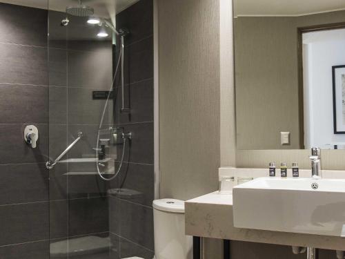 a bathroom with a shower and a toilet and a sink at Pullman Vina del Mar San Martin in Viña del Mar