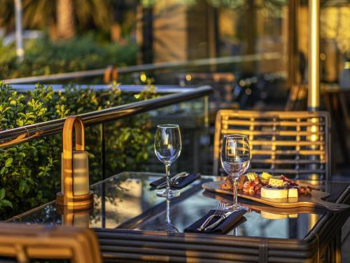 a table with two wine glasses and a plate of food at Pullman Vina del Mar San Martin in Viña del Mar