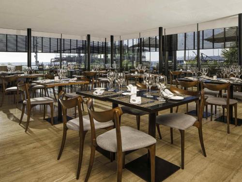 a restaurant with tables and chairs and windows at Pullman Vina del Mar San Martin in Viña del Mar