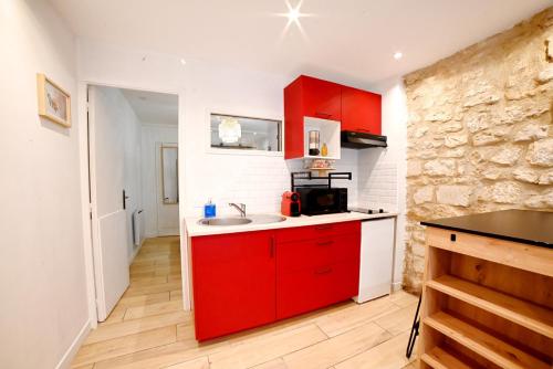 Una cocina con gabinetes rojos y un fregadero. en Le petit cocon, en Périgueux