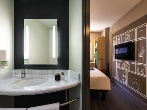 a bathroom with a sink with a mirror and a bed at Ibis Torreon in Torreón