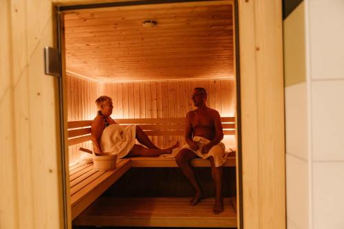 a man and woman sitting in a sauna at Landgoed Het Grote Zand in Hooghalen