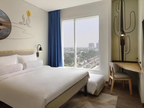 a hotel room with a bed and a large window at ibis Styles Jakarta Simatupang in Jakarta