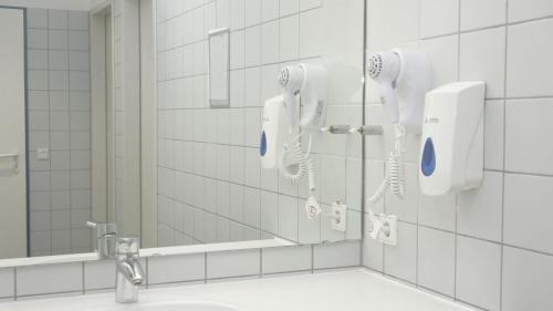 a bathroom with two hair dryers and a mirror at Low Budget Hostel in Munich