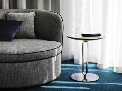 a living room with a chair and a side table at Hotel Chadstone Melbourne MGallery Collection in Chadstone