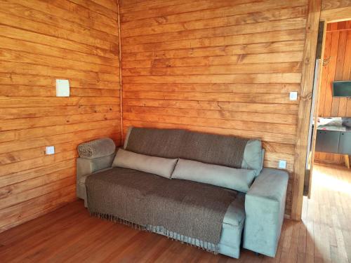 a couch sitting in a room with wooden walls at Eco Chalé Urupema in Urupema