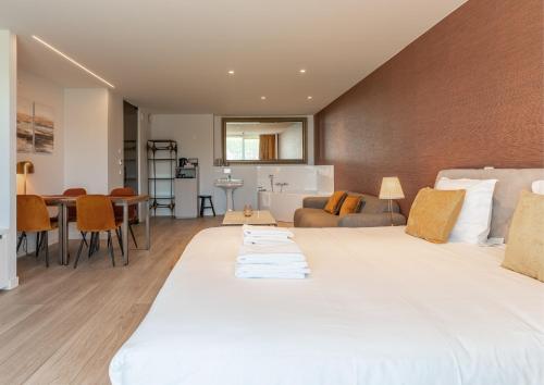 une chambre avec un grand lit blanc et un salon dans l'établissement Acropolis - Luxury Appartments I Hotelservice and parking, à Middelkerke
