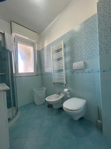 Un baño con azulejos azules, inodoro y lavabo. en Urban Sky Loft Fiumicino, en Fiumicino