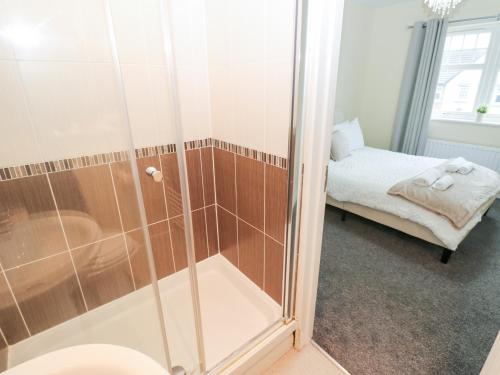 a bathroom with a shower and a bed in a room at Lingla House in Frizington