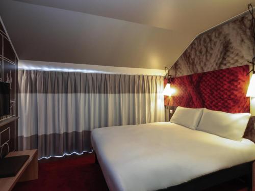 a bedroom with a large white bed in a room at ibis Cahors in Cahors