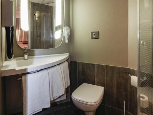 a bathroom with a toilet and a sink and a mirror at ibis Cahors in Cahors