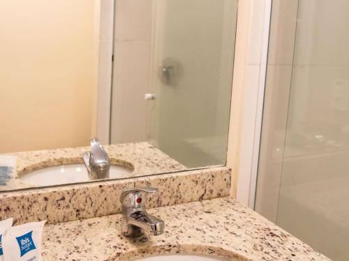 a bathroom with a sink and a mirror at ibis budget Itaperuna in Itaperuna