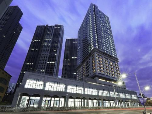a tall building with two tall skyscrapers in a city at Mercure Ambassador Ulsan in Ulsan