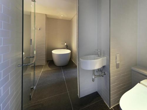 a bathroom with a sink and a glass shower door at Mercure Ambassador Ulsan in Ulsan