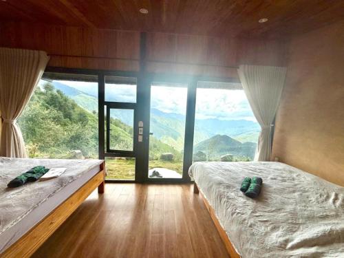 a bedroom with two beds and a large window with mountains at Samu Retreat Tà Xùa in Bắc Yên