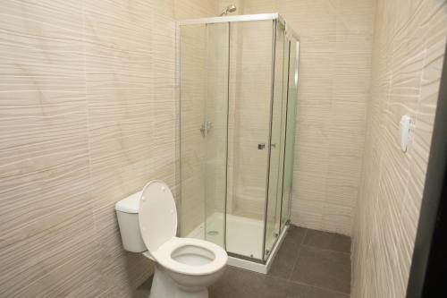a bathroom with a toilet and a glass shower at Nour apartments in São Tomé