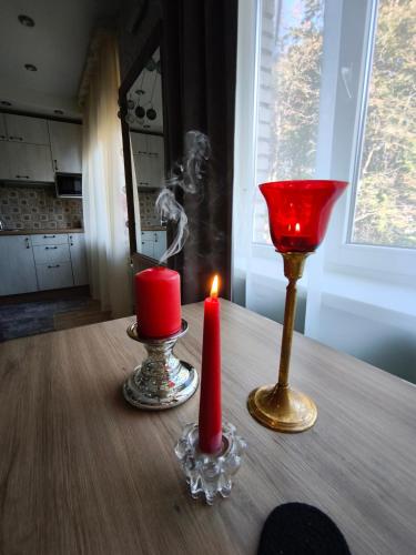 a table with two candles and a red candle holder at Narva Boho Home in Narva