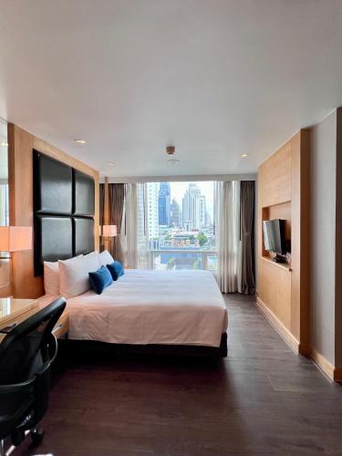 a hotel room with a bed and a desk and a window at Sora Resort & Suites Sukhumvit in Bangkok