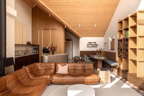 a living room with a leather couch and a kitchen at Kalbornia LAKE & POOL HOUSE by JWPM in Brzeźno Mazurskie