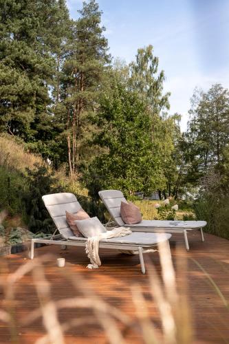 two white chairs sitting on a wooden deck at Kalbornia LAKE & POOL HOUSE by JWPM in Brzeźno Mazurskie