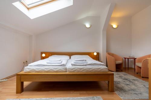 a bedroom with a bed with white sheets and a skylight at Hotel Arkada in Levoča