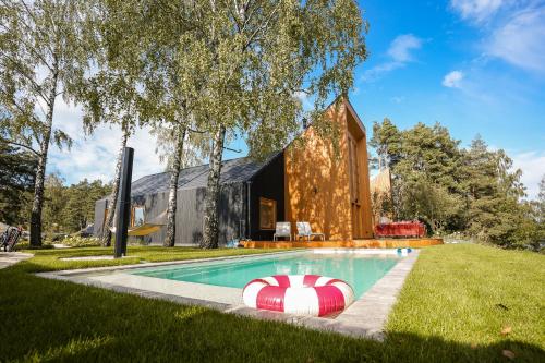 a house with a swimming pool in the grass at Kalbornia LAKE & POOL HOUSE by JWPM in Brzeźno Mazurskie
