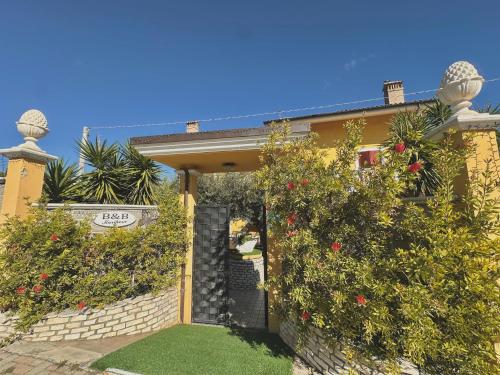 a yellow house with a gate and some bushes at B&B Mariposa in Collecorvino