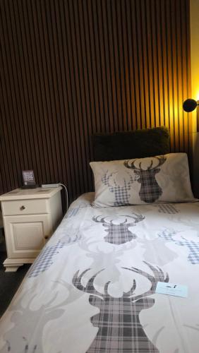 a bed with a black and white comforter and a night stand at The Gables Whisky B&B in Dufftown