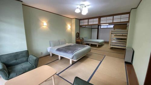a bedroom with a bed and a couch and a chair at Nona Madarao in Madarao Kogen