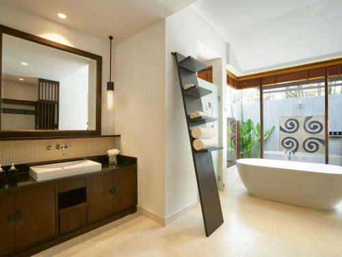 a bathroom with a tub and a large mirror at Mövenpick Asara Resort & Spa Hua Hin in Hua Hin