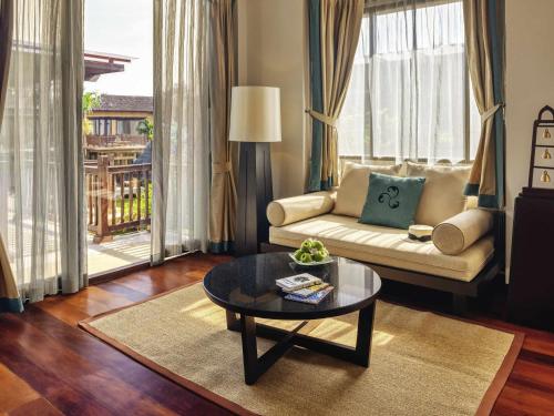 a living room with a couch and a coffee table at Mövenpick Asara Resort & Spa Hua Hin in Hua Hin