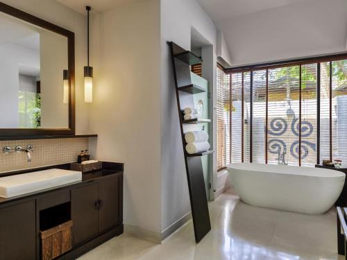 a bathroom with a tub and a sink and a window at Mövenpick Asara Resort & Spa Hua Hin in Hua Hin