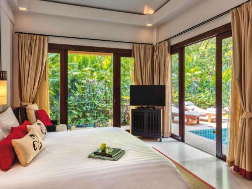 a bedroom with a bed with a television and a patio at Mövenpick Asara Resort & Spa Hua Hin in Hua Hin