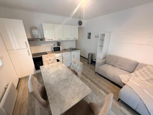 a kitchen and living room with a table and a couch at Résidence des Fleurs in Cabourg