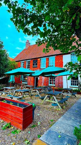 a group of picnic tables with umbrellas in front of a building at The Bull Inn in Little Walsingham