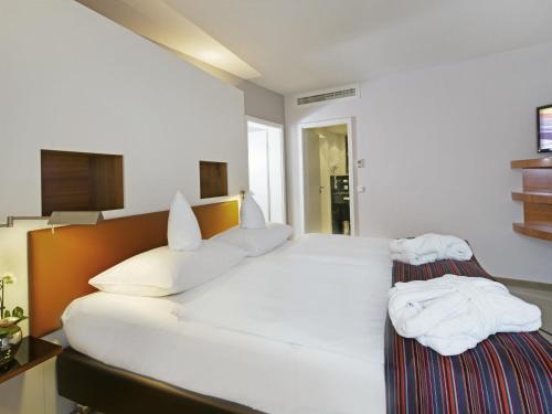 a bedroom with a large white bed with towels on it at Mövenpick Hotel Münster am Aasee in Münster