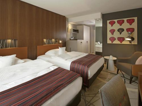 a hotel room with two beds and a living room at Mövenpick Hotel Münster am Aasee in Münster