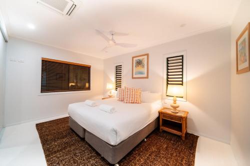 a white bedroom with a bed and two lamps at Beachside on Pacific in Mission Beach