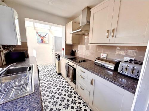 eine Küche mit weißen Schränken und einem schwarz-weißen Fliesenboden in der Unterkunft Entire house in central Bournemouth, sleeps 8, 13 min walk to beach in Bournemouth