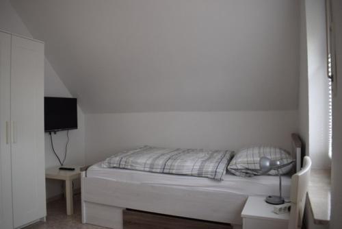 a white bedroom with a bed and a television at Sögel HA01 in Sögel