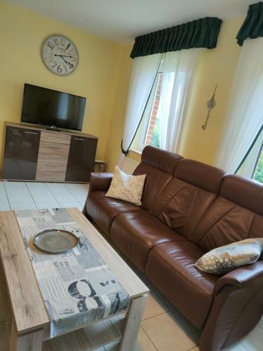 a living room with a brown leather couch and a tv at Sögel HA01 in Sögel