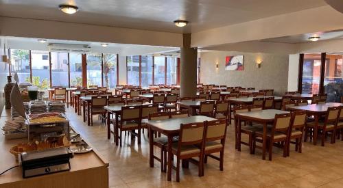 a dining room with tables and chairs and windows at Boulevard da Praia Apart Hotel - Porto Seguro - Frente da Praia de Taperapuan in Porto Seguro