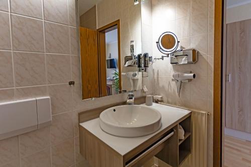 un baño con lavabo y espejo en Hotel ELBRIVERA Alt Prester, en Magdeburgo