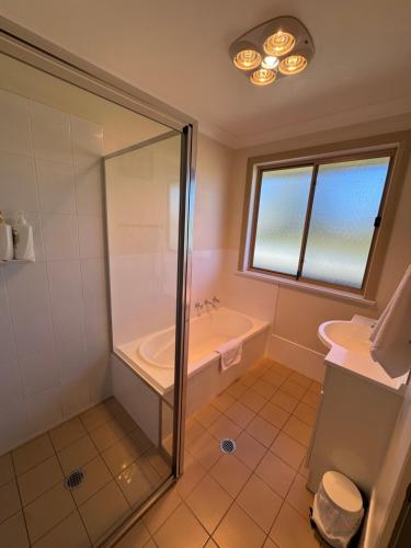 Un baño con ducha, bañera y lavabo. en Comfy and relaxing stay - Rest Easy Mudgee Cottage, en Mudgee